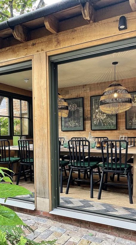 No. 23 — the garden room through open doors, botanical prints and rattan lights