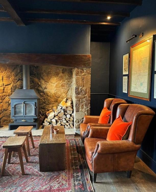 The Nevill Arms — leather club armchairs, Yorkshire milking stools, an antique rug and a 17th-century Welsh coffer by the wood-burner, with framed antique maps