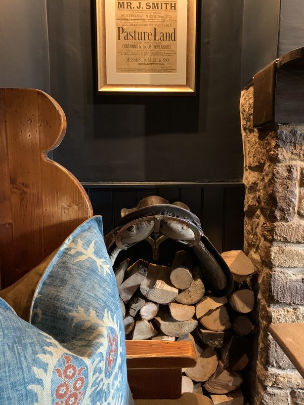 The Nevill Arms — the framed 1879 auction notice naming the inn, an antique saddle on the log store